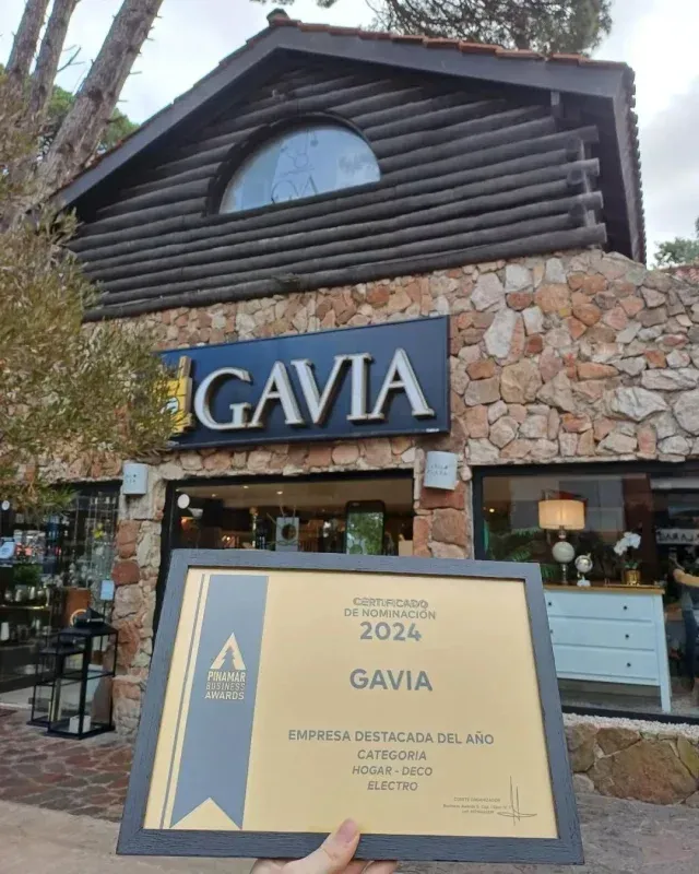 Una persona que sostiene un certificado frente a un edificio que dice gavia