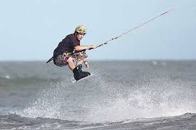 Un hombre está volando por el aire mientras monta una ola en una tabla de surf en el océano.