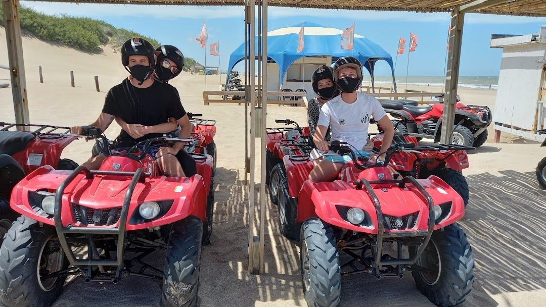 Un grupo de personas viajan en vehículos todo terreno por la playa.