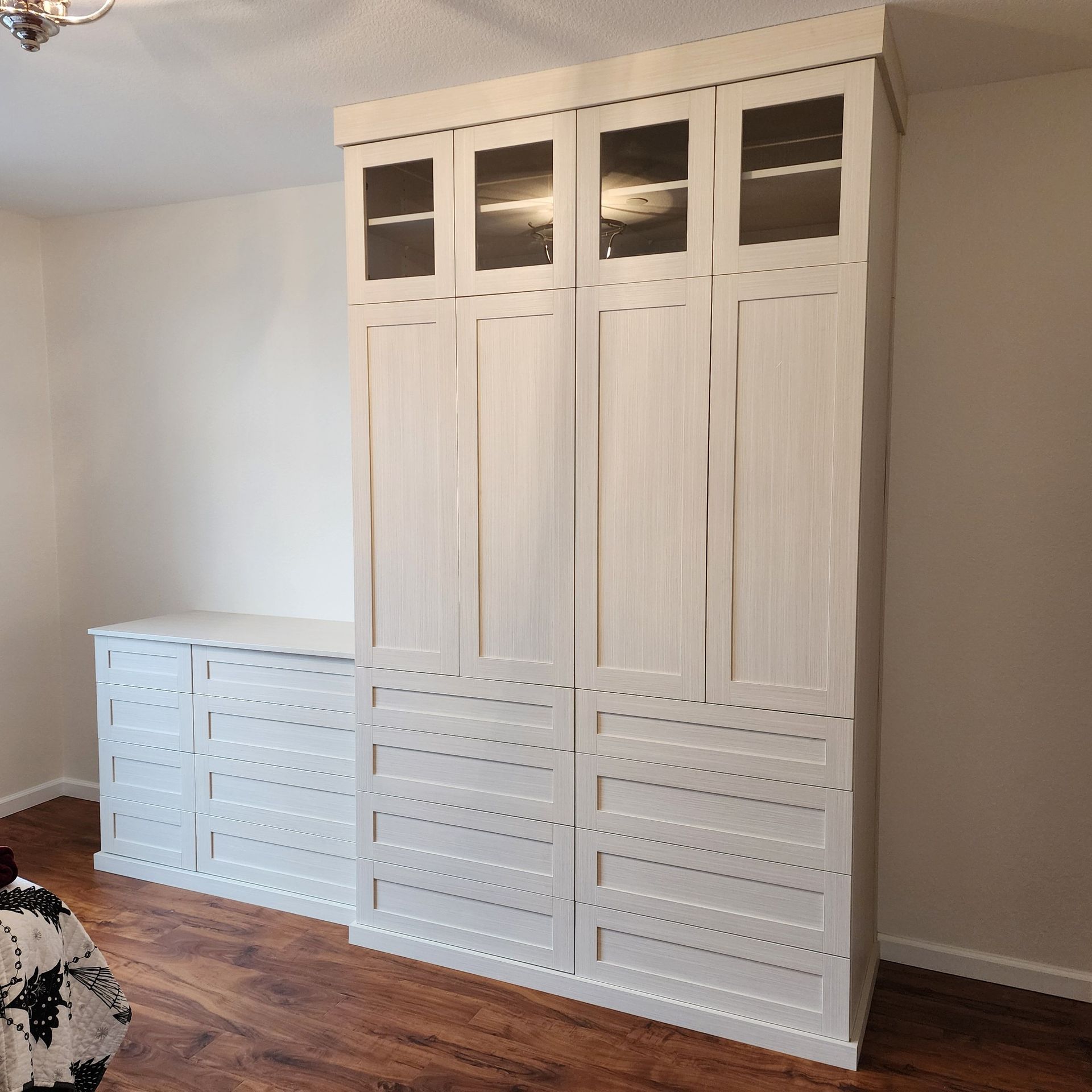 A bedroom with a large white cabinet with glass doors