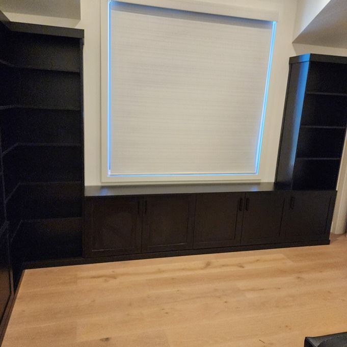 A living room with black cabinets and a window with blinds