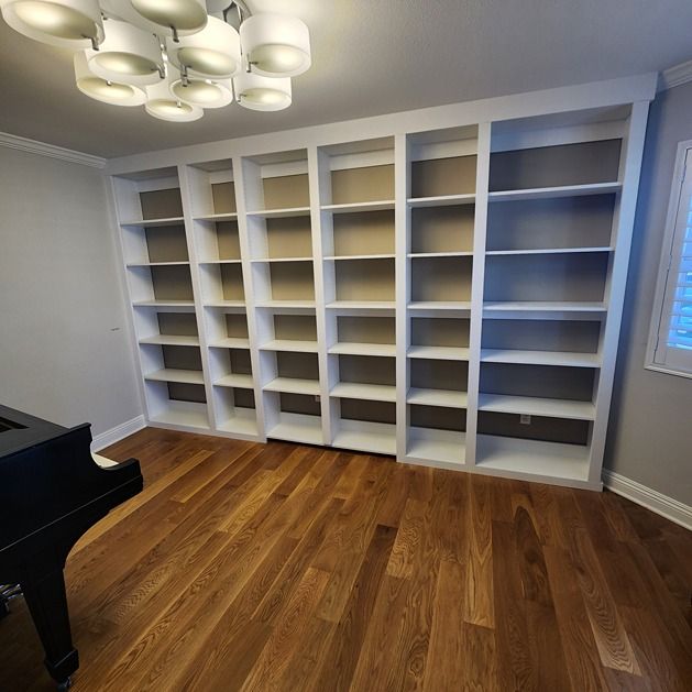 There is a piano in the room with a lot of shelves.