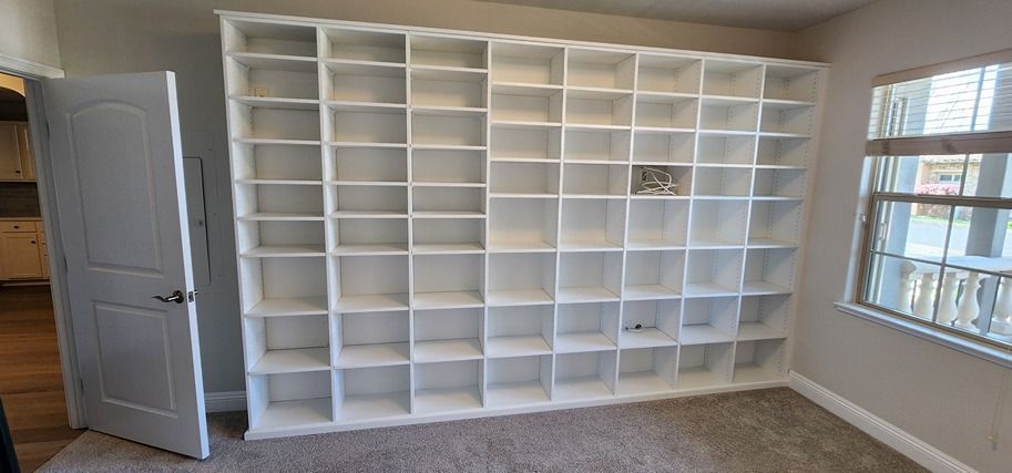 A room with a lot of shelves and a window.