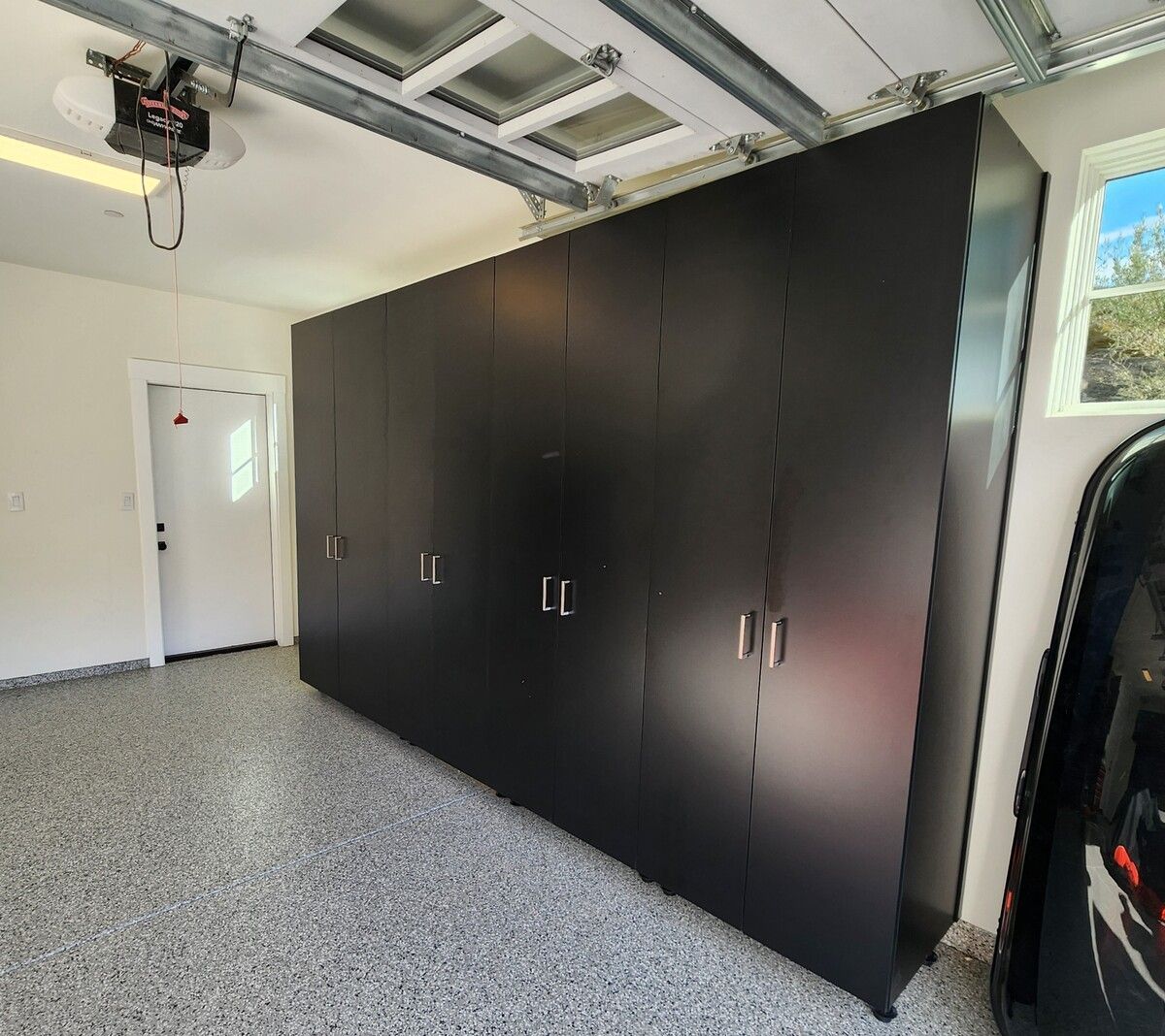 A garage with a lot of black cabinets and a garage door opener.