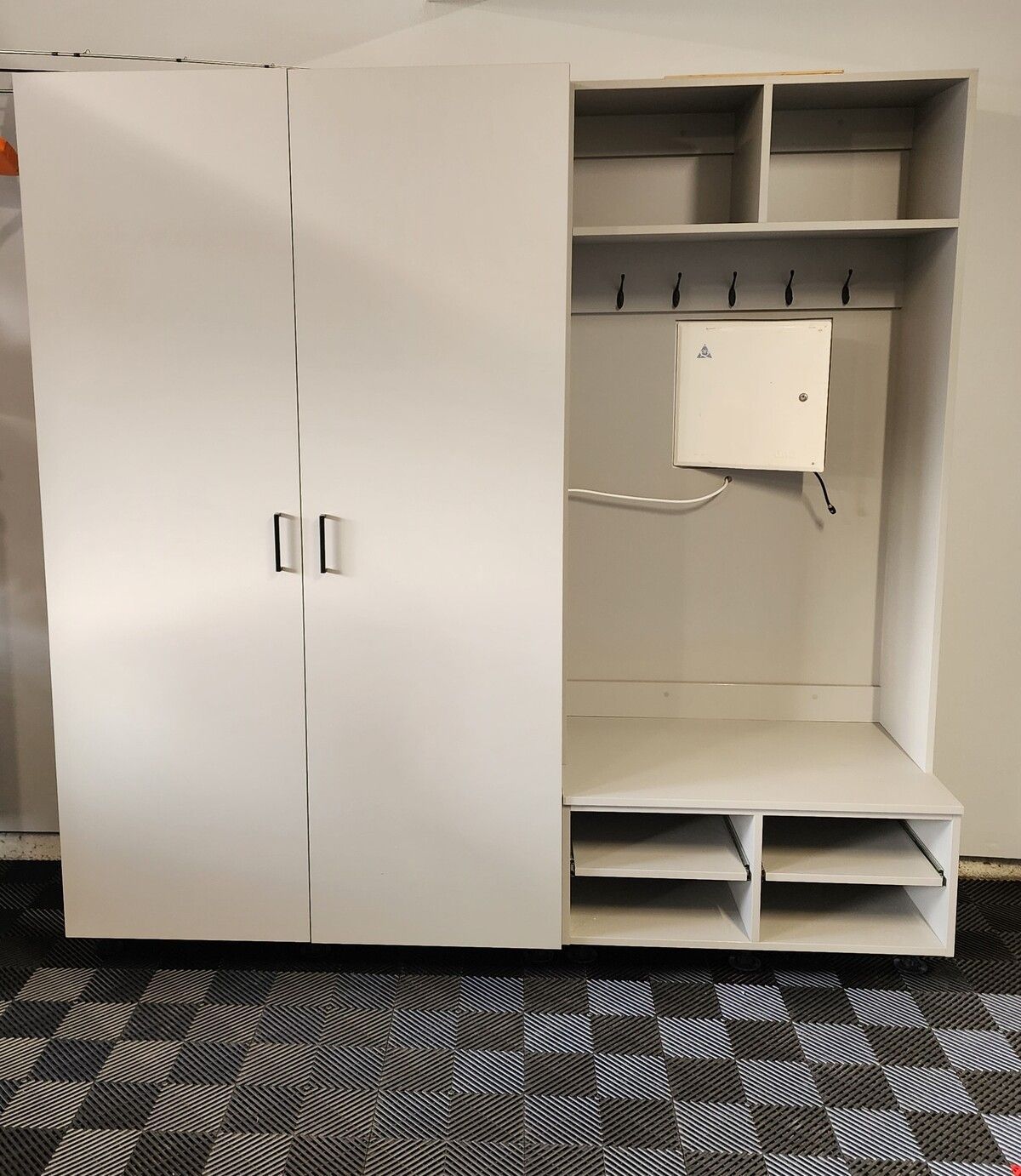 A white cabinet with hooks and shelves in a garage