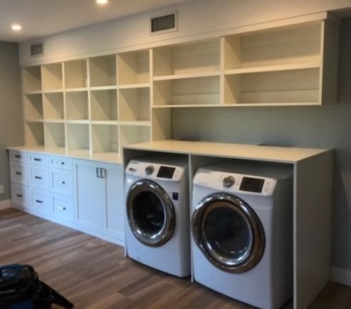A laundry room with two washing machines and shelves