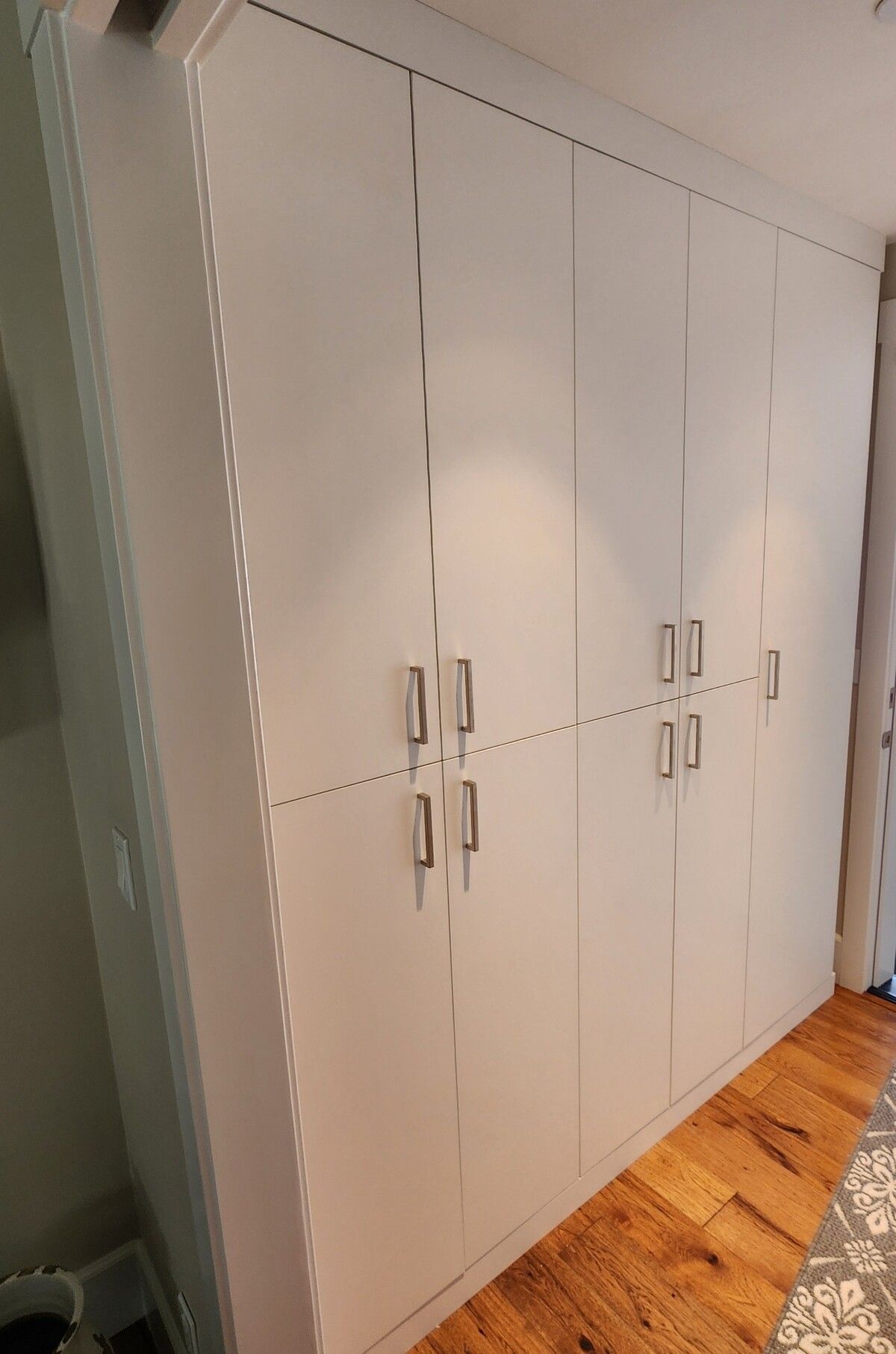 A large white cabinet with a wooden floor in a room.