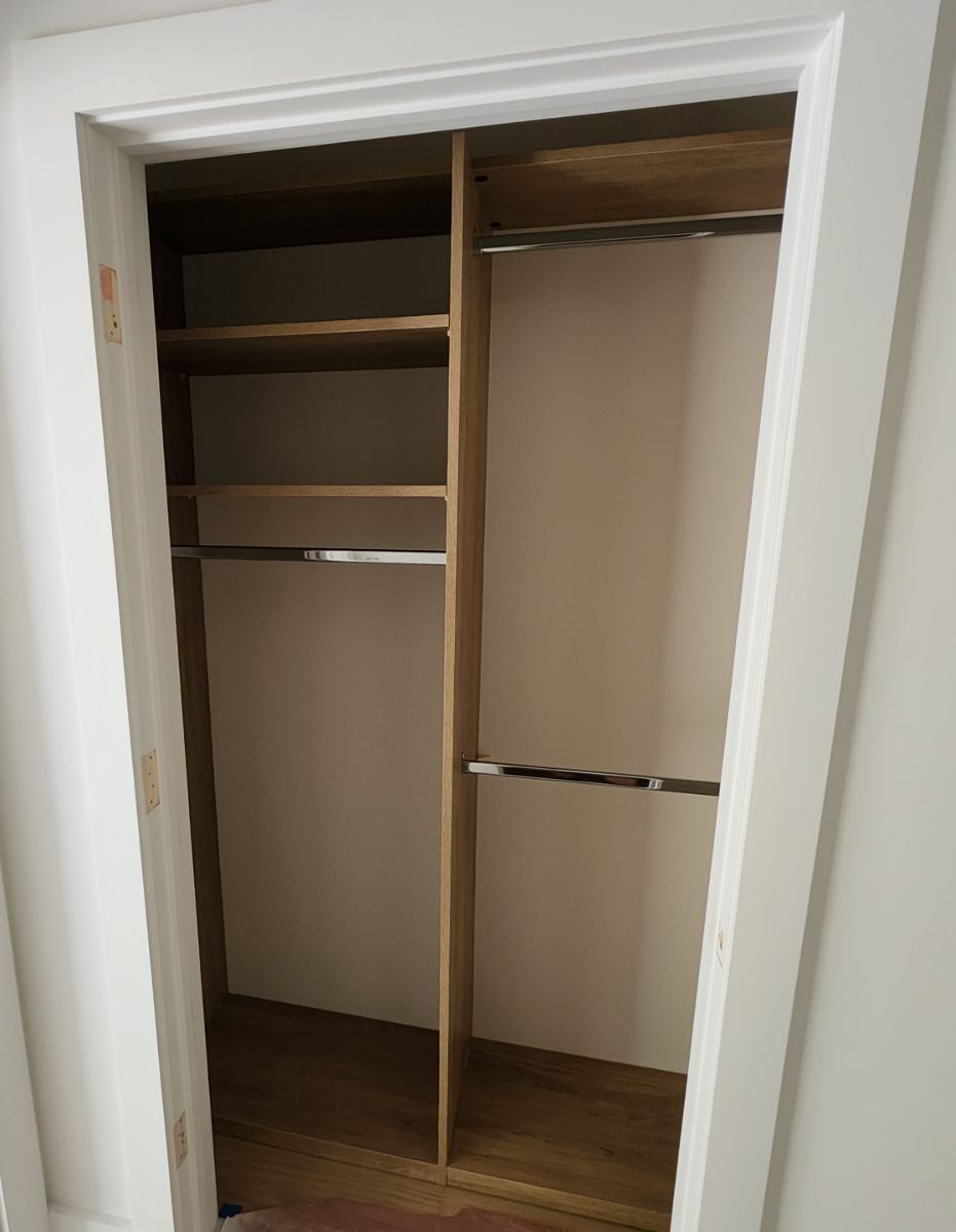 An empty closet with wooden shelves and clothes racks.