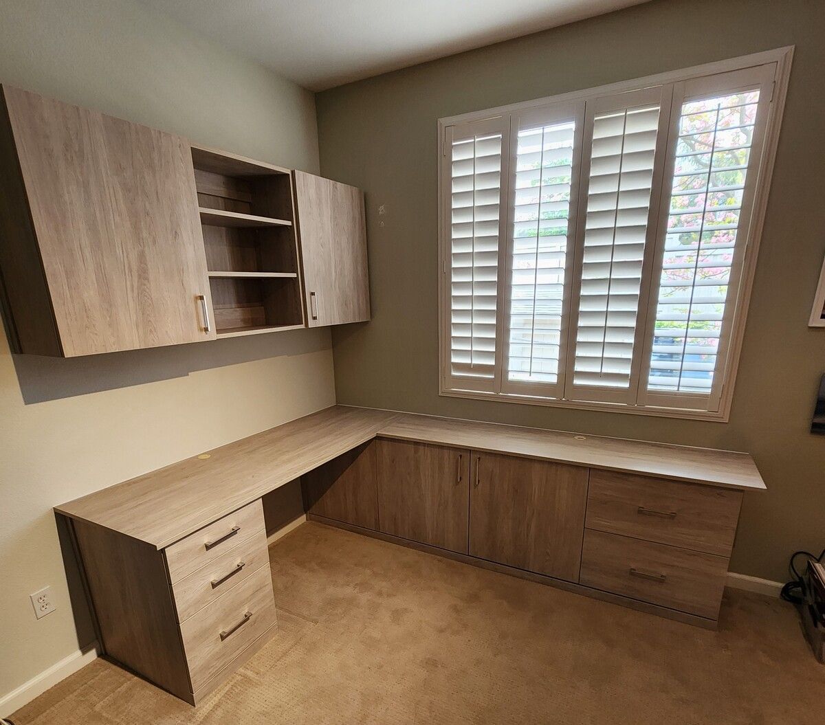 A  home office room with a desk and a window with shutters