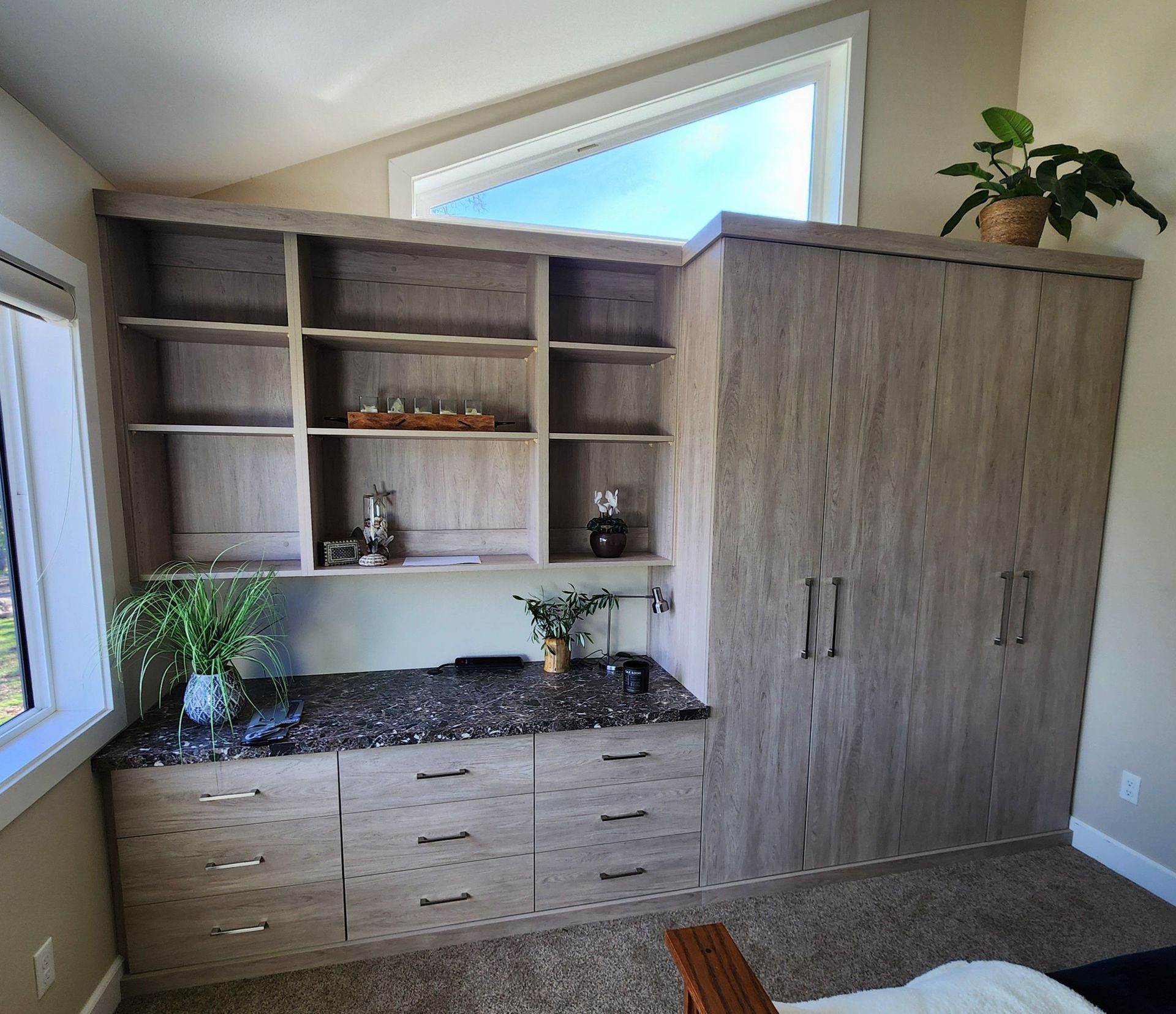 A room with a lot of shelves and drawers and a window