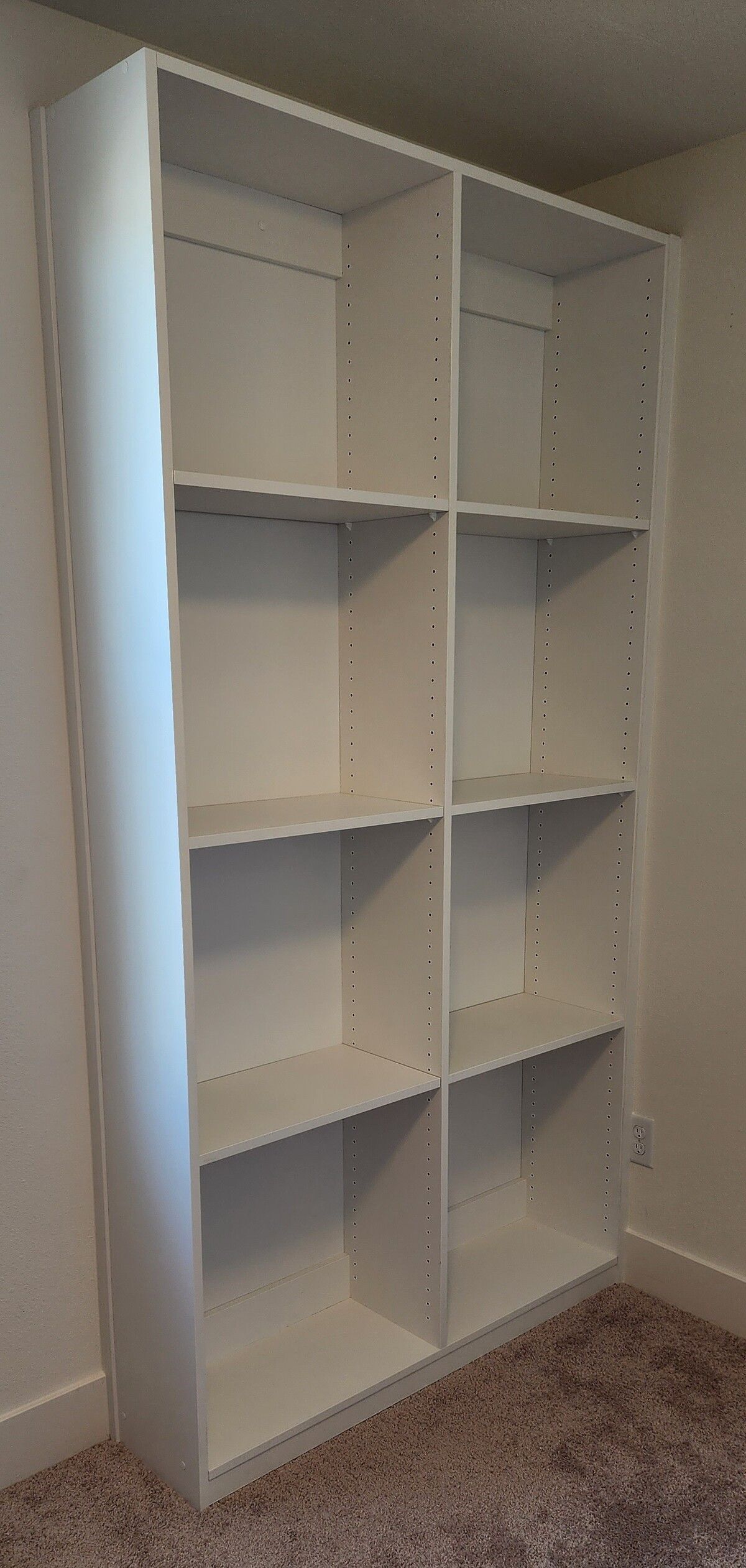 A white bookshelf is sitting in a room next to a wall.