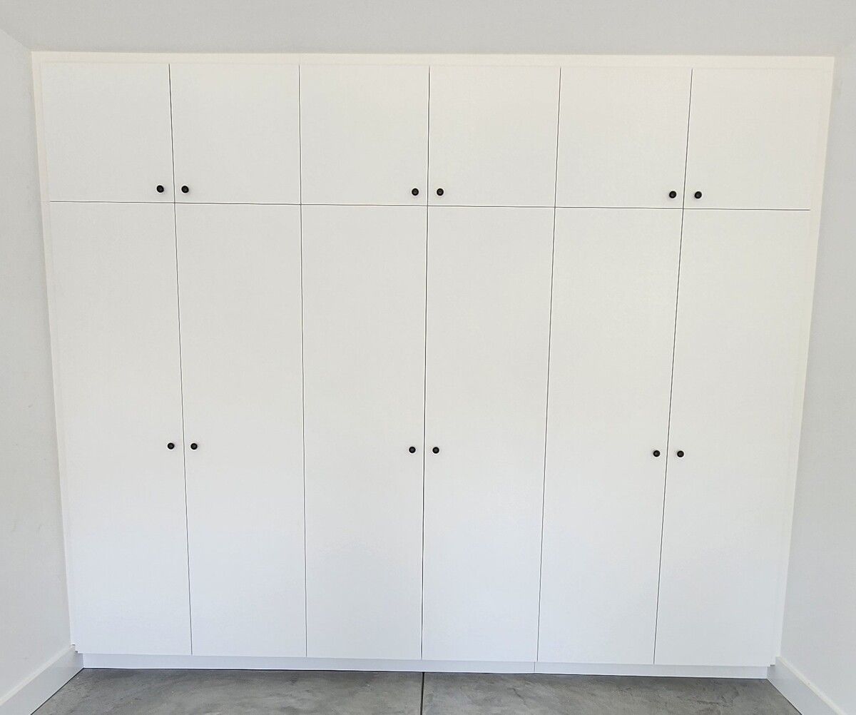 A room with a lot of white cabinets and a concrete floor.
