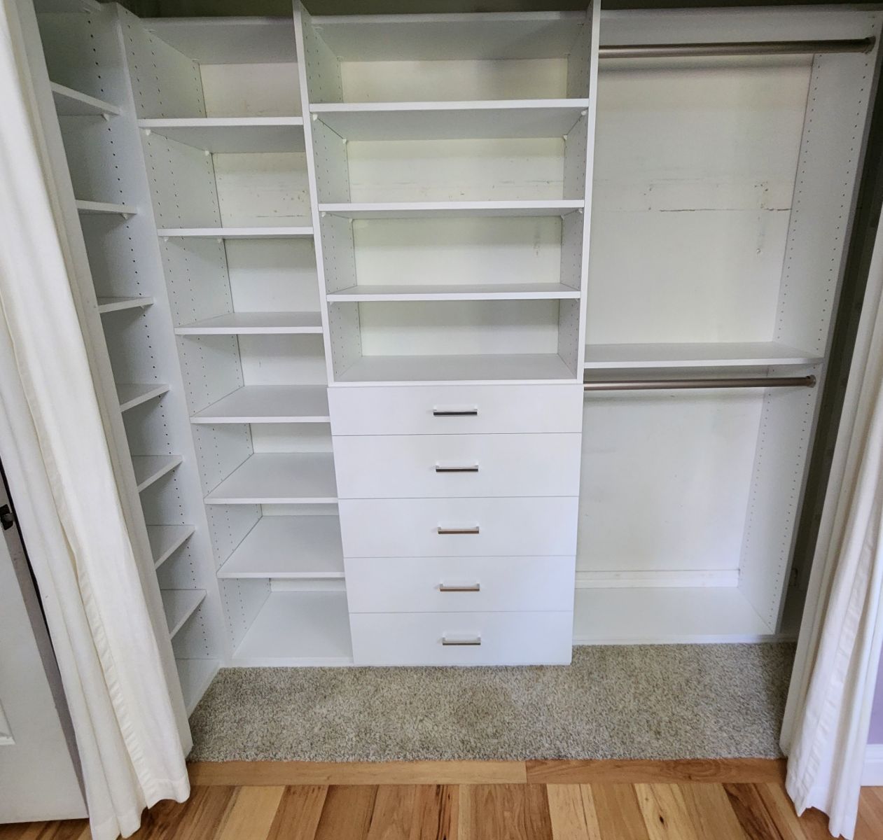 A walk in closet with lots of shelves and drawers