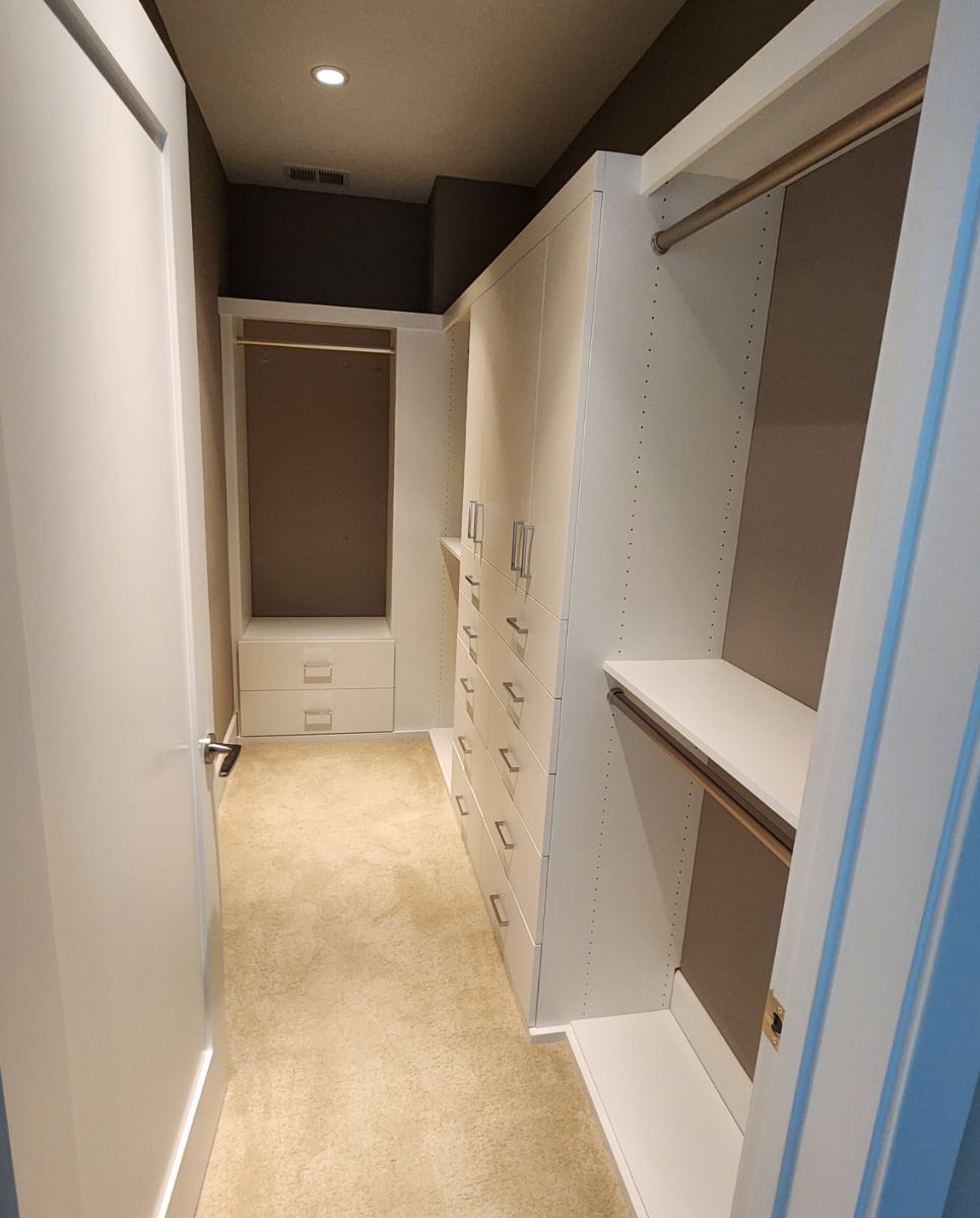 A walk in closet with lots of shelves and drawers