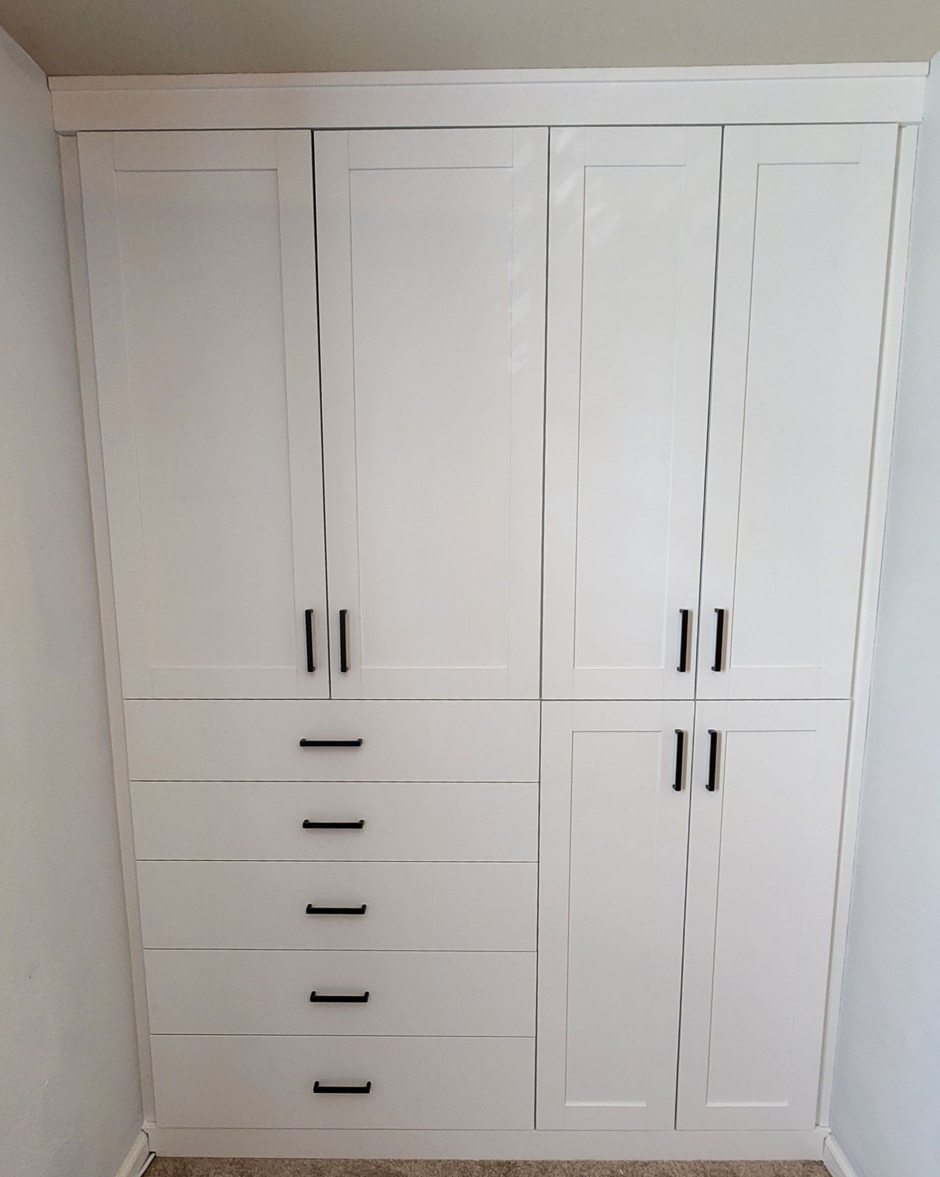A large white cabinet with drawers and doors in a room.