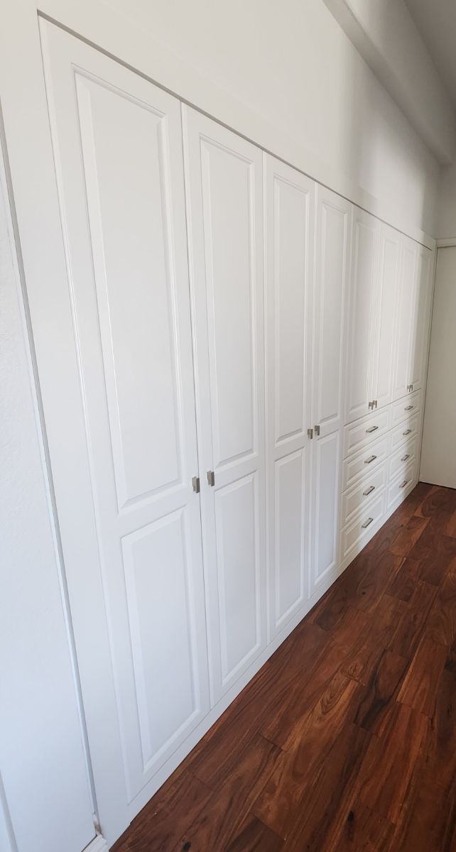 There are a lot of white cabinets and drawers in this room.
