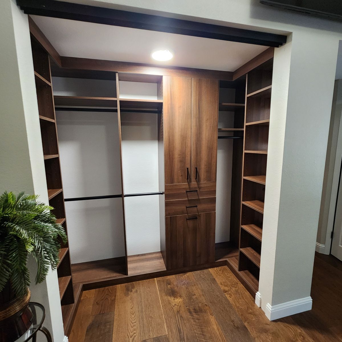 Custom walk-in closet with dark wood shelves and cabinet on wood floor.