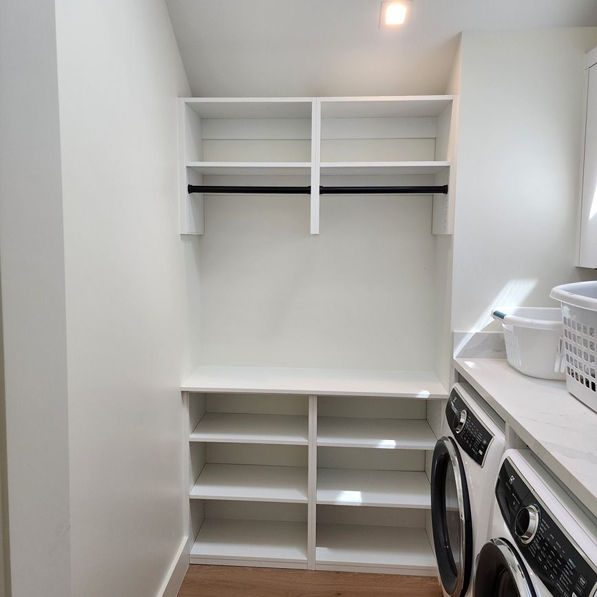 A laundry room with a washer and dryer and shelves