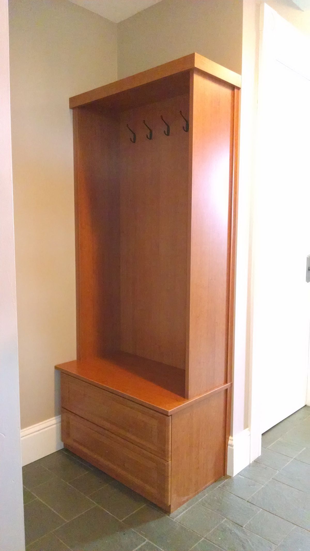 A hallway with a wooden coat rack and a bench.