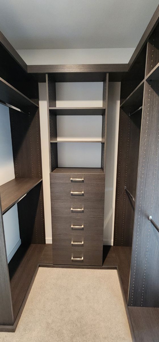 A walk in closet with lots of shelves and drawers.