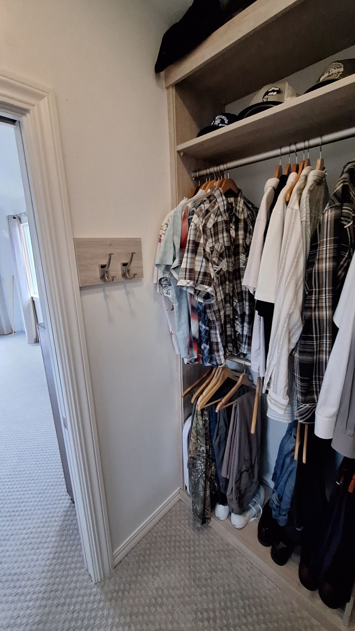 Walk-in closet with clothes hanging on racks, a top shelf, and a doorway to a bedroom.