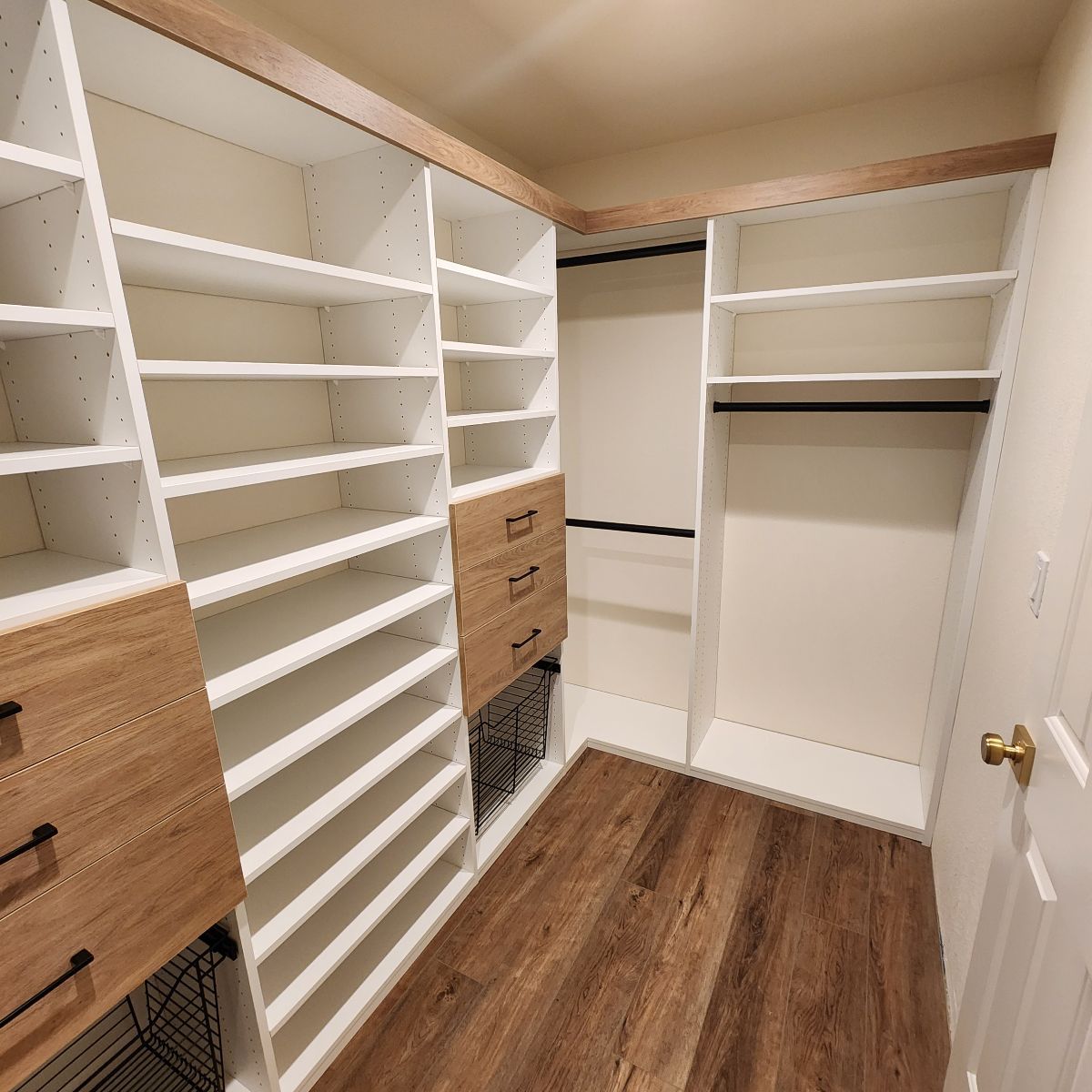 Custom closet organization system with shelves, drawers, and hanging rods. Light wood and white.