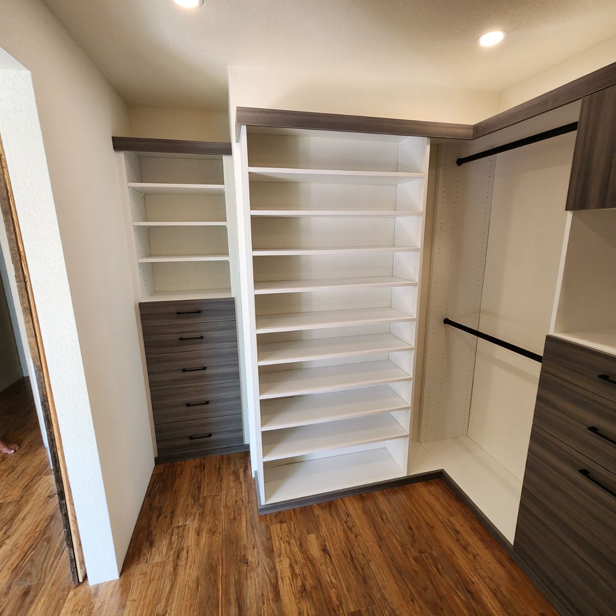 Custom closet organization system with shelves, drawers, and hanging rods; brown and white.