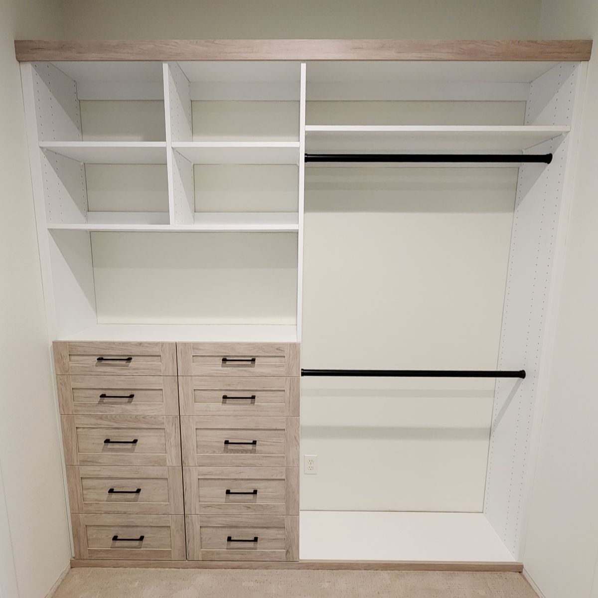 Reach In Closet with light wood shelves, drawers, and hanging rods against a white wall.