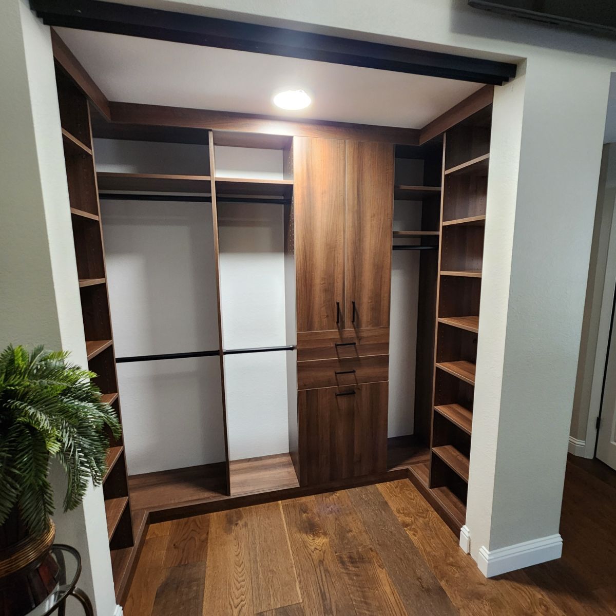 A walk in closet with wooden shelves and cabinets