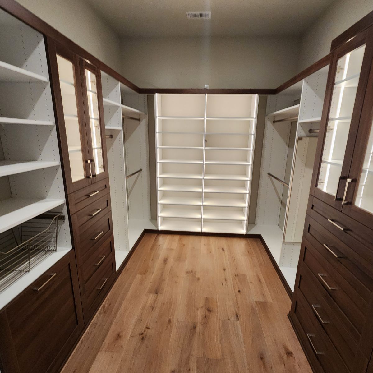 A walk in closet with lots of shelves and drawers