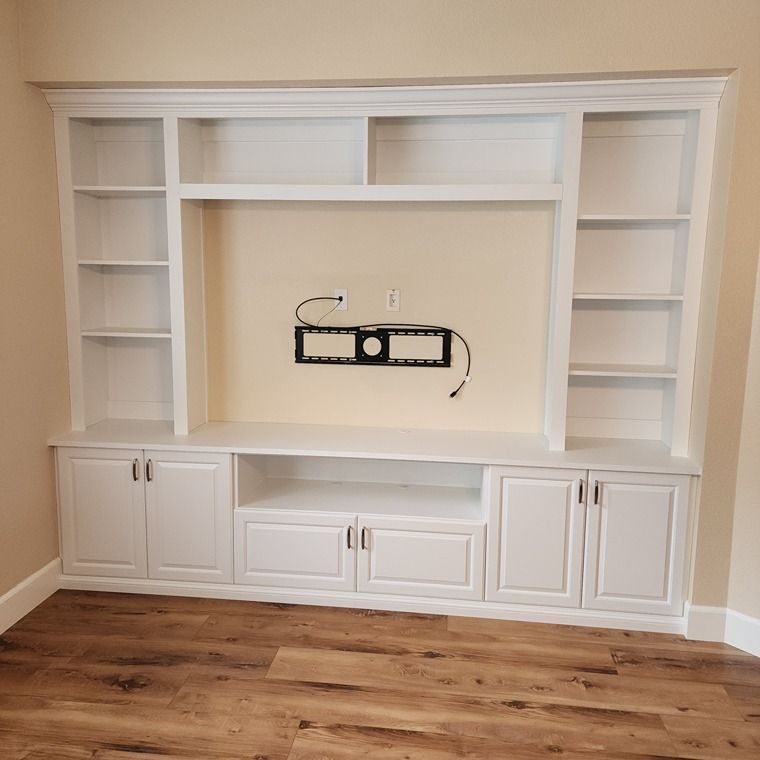 A white entertainment center with a flat screen tv mounted on the wall.