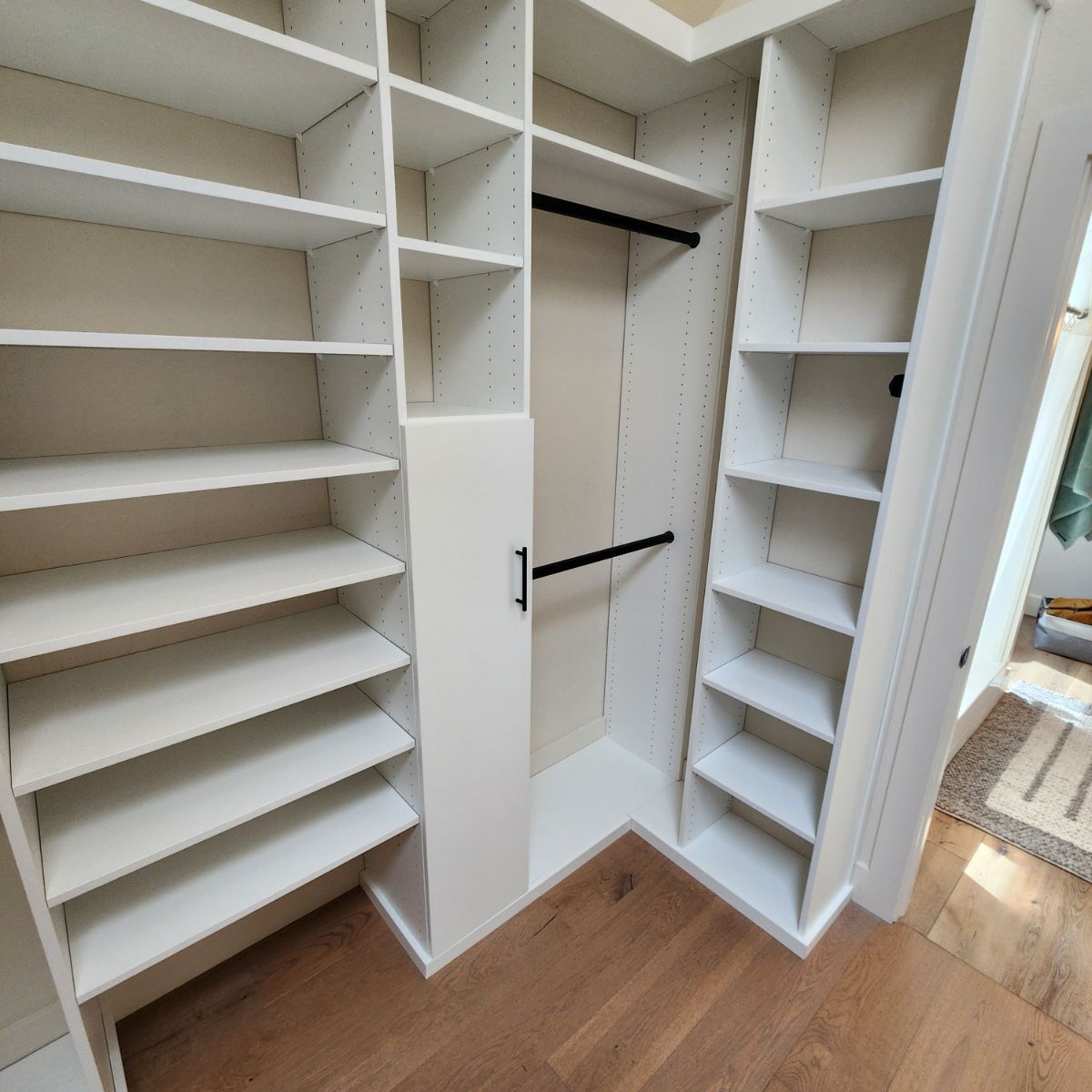 A walk in closet with lots of shelves and a hanging rail.