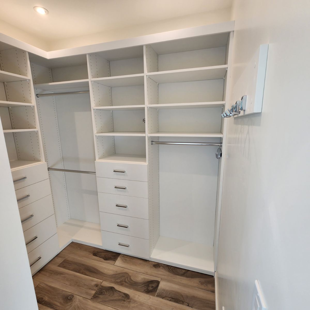 A walk in closet with lots of shelves and drawers.