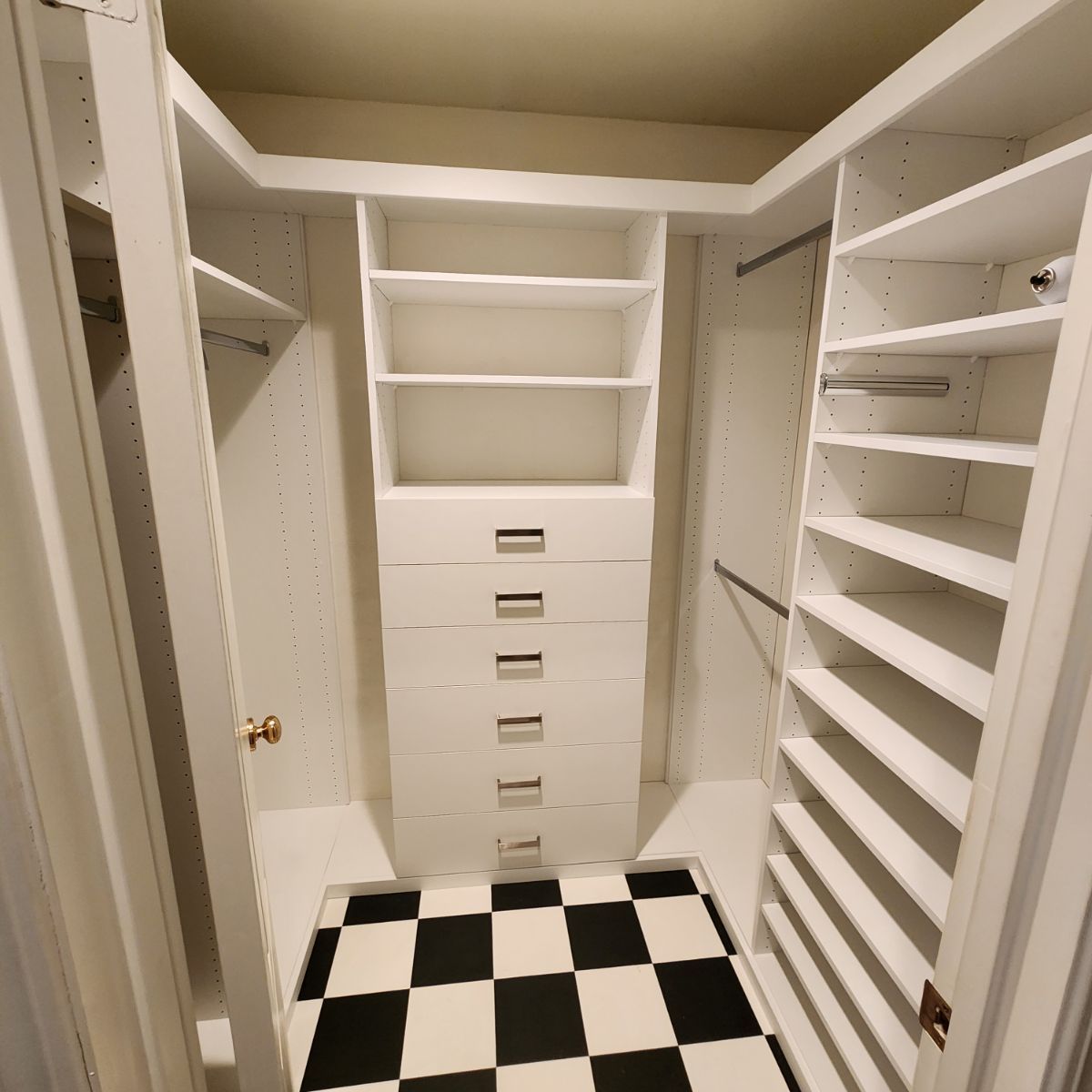 A walk in closet with lots of shelves and drawers