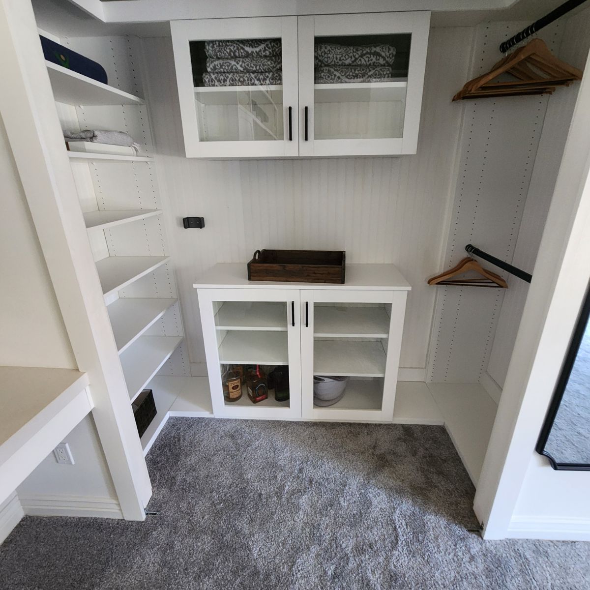 A walk in closet with shelves and cabinets and a mirror