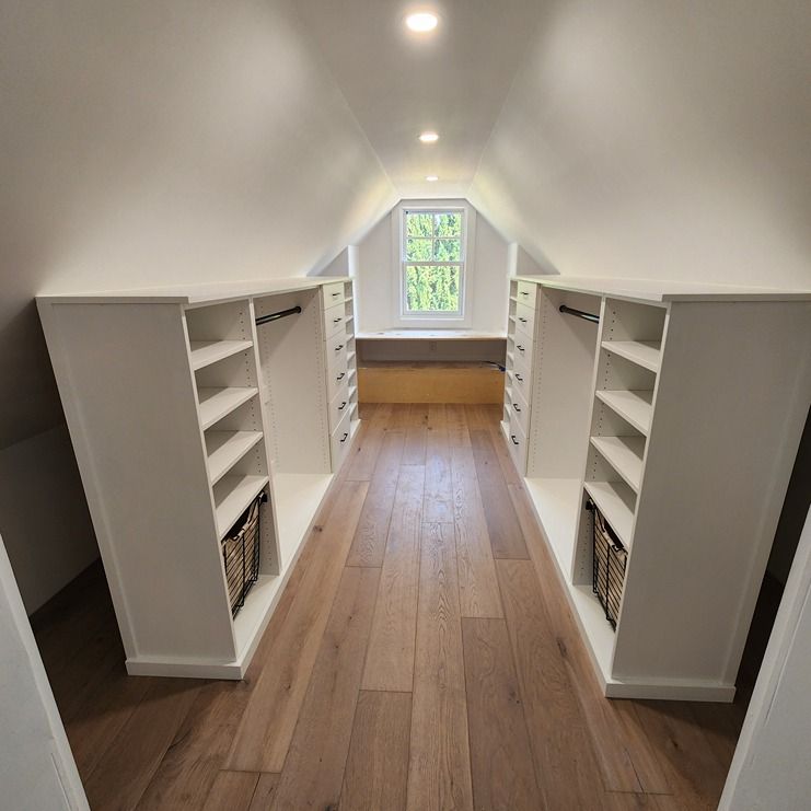 A walk in closet with hardwood floors and white shelves