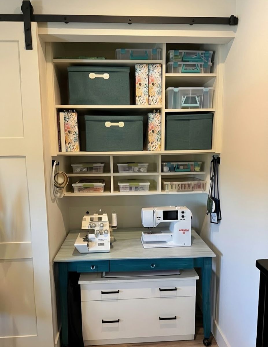 A sewing machine sits on a desk in a closet