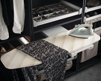 An ironing board with an iron on it is in a closet.