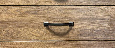 A close up of a wooden drawer with a black handle.