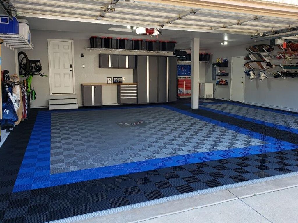 Garage with checkerboard blue and gray floor, cabinets, and storage.