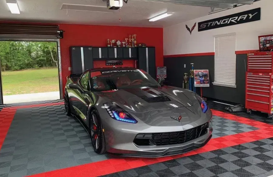 A gray sports car is parked in a garage.
