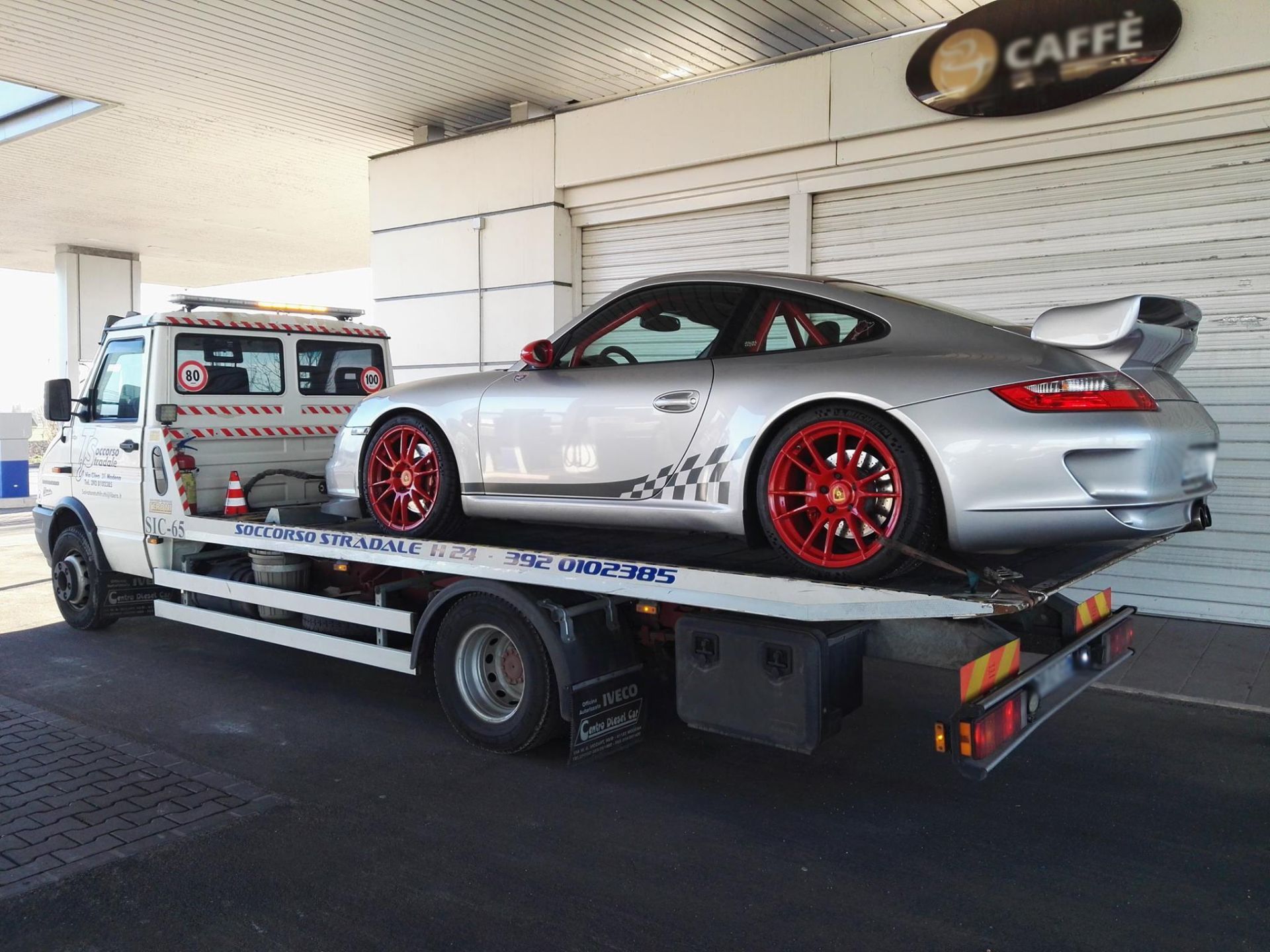 Una porsche argentata viene trainata da un carro attrezzi