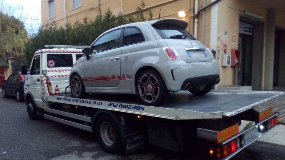 Un'auto bianca è parcheggiata sopra un carro attrezzi.