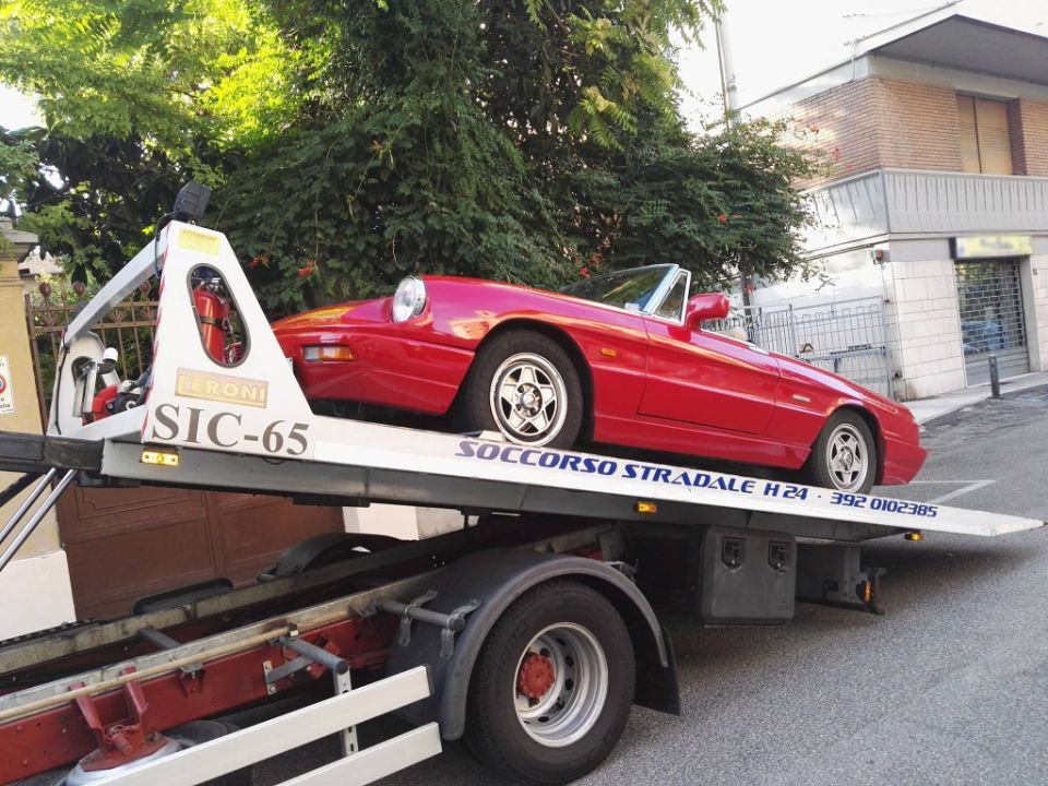 Un'auto sportiva rossa viene trainata da un carro attrezzi.