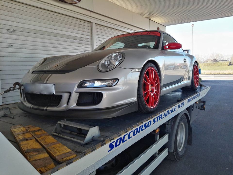 Una porsche argentata è parcheggiata sopra un carro attrezzi.