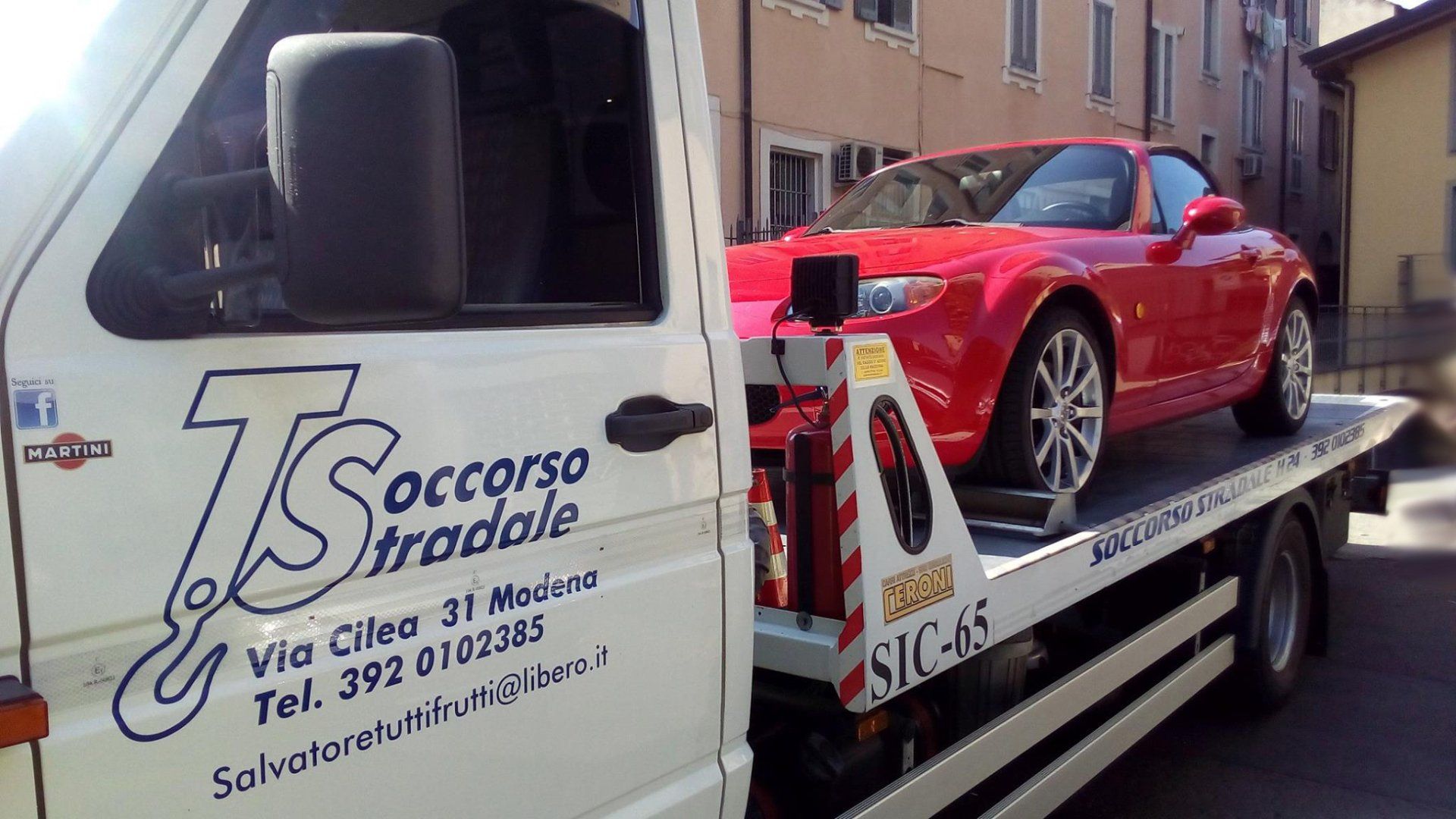 Un'auto rossa è sul retro di un carro attrezzi