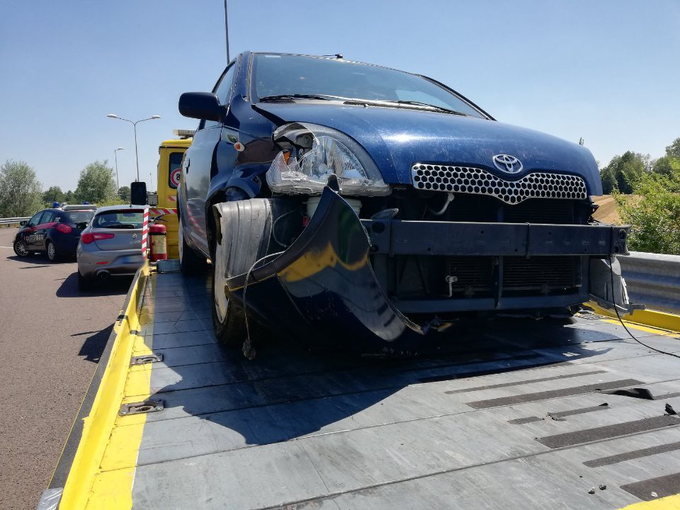 Un'auto blu è parcheggiata sopra un carro attrezzi giallo.