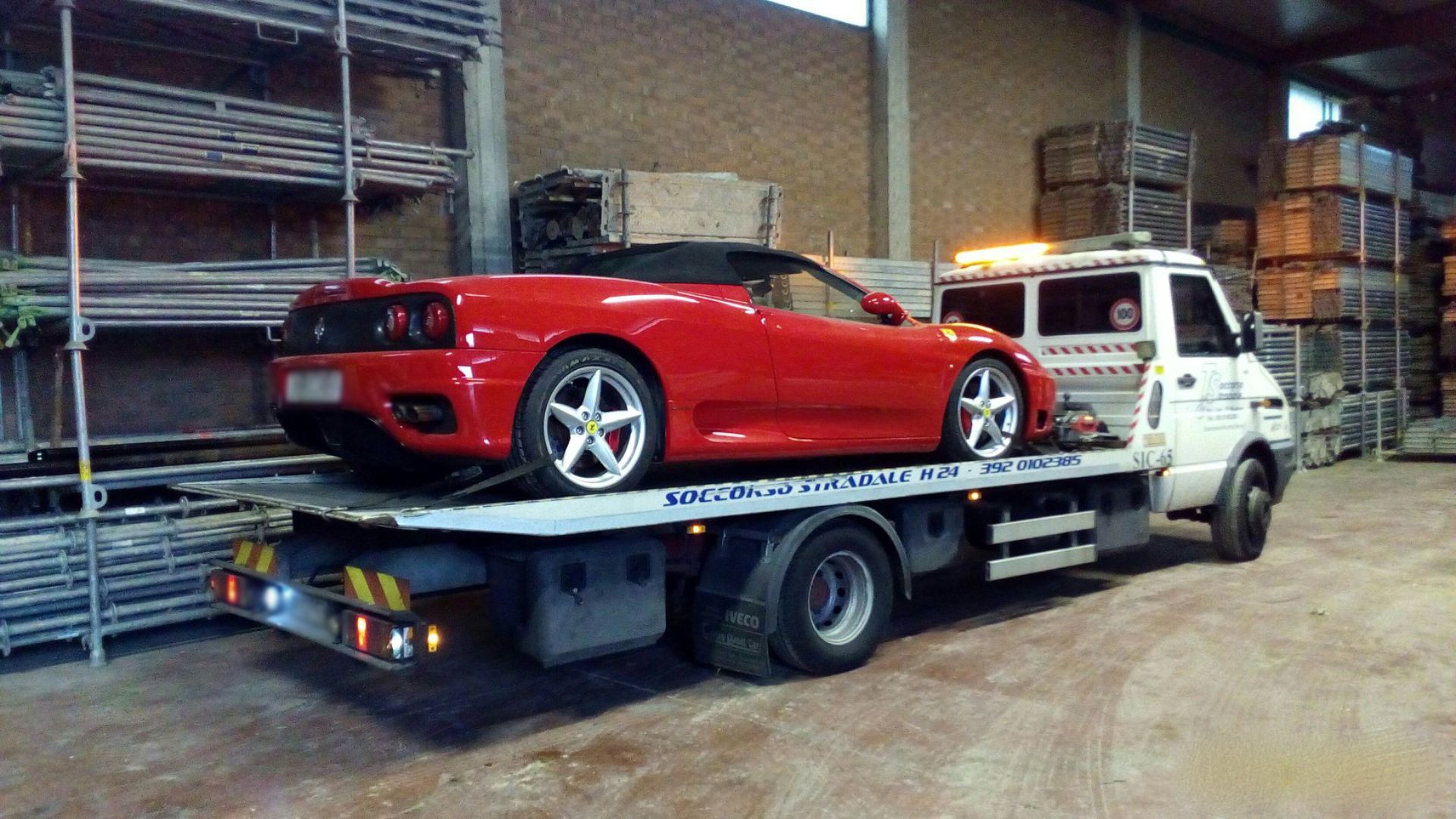 Un'auto sportiva rossa è sul retro di un carro attrezzi