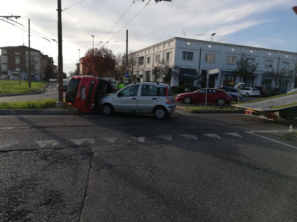Un'auto rossa è capovolta sul ciglio della strada