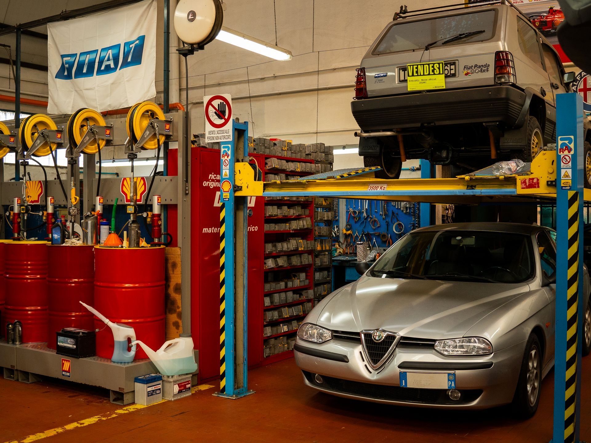 Un'alfa romeo argentata è su un ponte sollevatore in un garage